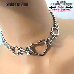 Submissive day collar, with center heart shaped ring and Gothic side-stabilizing ornaments, affixed by 8 sturdy jump rings with the bulk of the collar being 8mm curb chain; 24/7 wear waterproof, all stainless steel; will never tarnish; reusable permanent locking clasp option.