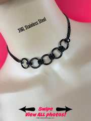 submissive day collar; black stainless steel, featuring 5 center rings secured by sturdy double jump rings, affixed to sparkly 6mm curb chain; waterproof and locking option